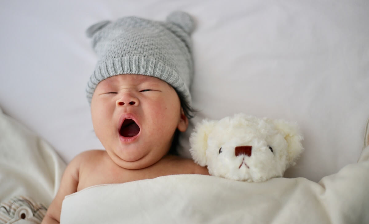 Baby yawning which in bed wearing an overnight cloth nappy